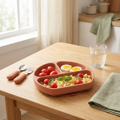 Assiette ventouse en silicone terracotta à trois compartiments garnie, posée sur une table en bois