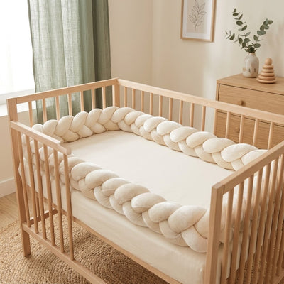 Tresse de lit crème en velours le long d'un lit à barreaux en bois clair