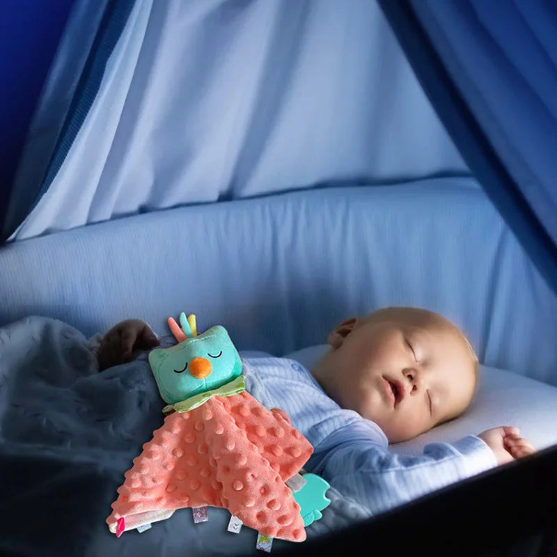 doudou hibou rose à tête bleue tenant compagnie à un enfant endormi dans son berceau bleu habillé en bleu avec une couverture bleue