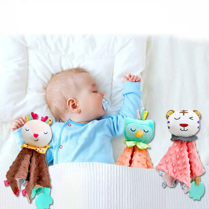 Doudou Hiboux Carré Rose à tête bleu et aux yeux fermés, doudou carré cerf marron à tête beige et doudou tigre rose à tête blanche  accompagnant le sommeil d'un bébé au lit