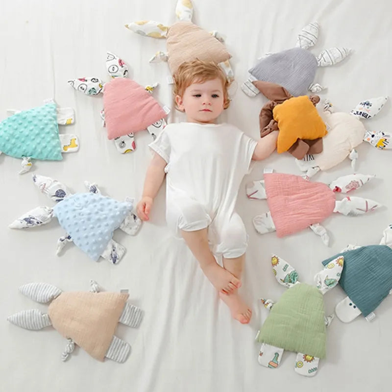 enfant allongé au milieu d'un cercle de 10 doudous lapin AUBIN et un onzième est dans sa main gauche doudou lapin / doudou rose / doudou bleu / doudou blanc / doudou plat / doudou gris /  doudou rose et blanc / doudou bébé / nouveau-né / cadeau nouveau-né / enfant / enfance Image
