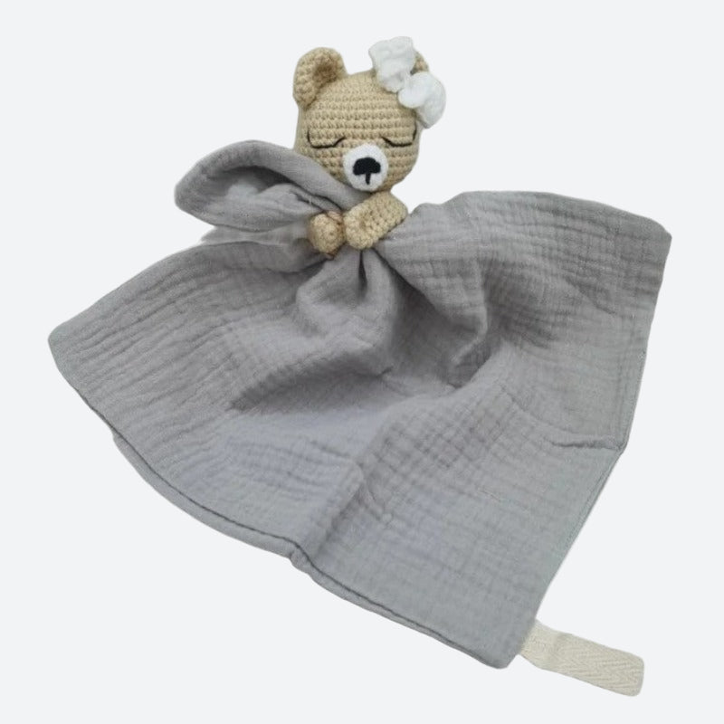 FATIMA est un adorable doudou plat représentant un ours au crochet. Doté d'un noeud blanc sur la tête, il tient un mouchoir ou carré de gaze de coton entre ses pattes pour offrir douceur et réconfort à votre enfant. Disponible en quatre coloris : Écru, Marron, Bleu et Vieux rose. BLEU