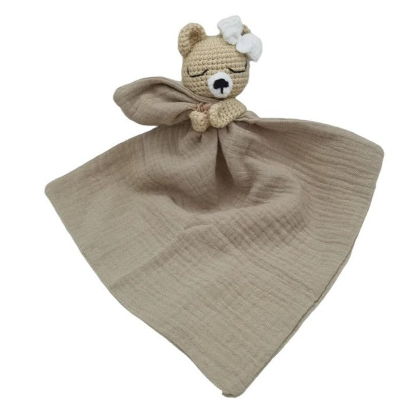 FATIMA est un adorable doudou plat représentant un ours au crochet. Doté d'un noeud blanc sur la tête, il tient un mouchoir ou carré de gaze de coton entre ses pattes pour offrir douceur et réconfort à votre enfant. Disponible en quatre coloris : Écru, Marron, Bleu et Vieux rose. MARRON