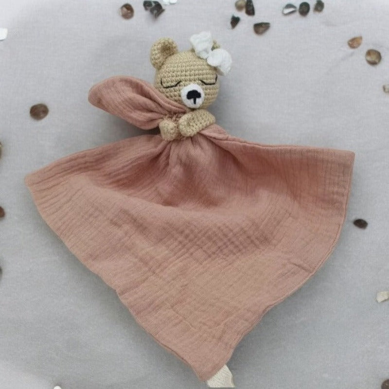 FATIMA est un adorable doudou plat représentant un ours au crochet. Doté d'un noeud blanc sur la tête, il tient un mouchoir ou carré de gaze de coton entre ses pattes pour offrir douceur et réconfort à votre enfant. Disponible en quatre coloris : Écru, Marron, Bleu et Vieux rose. ROSE