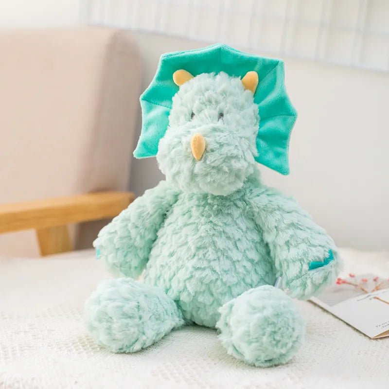 peluche dinosaure bleu posé sur un tissu blanc avec une carte aux motifs floraux à coté