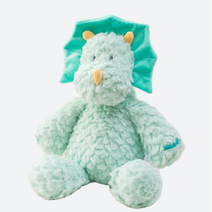 peluche dinosaure bleu posé sur un tissu blanc avec une carte aux motifs floraux à coté