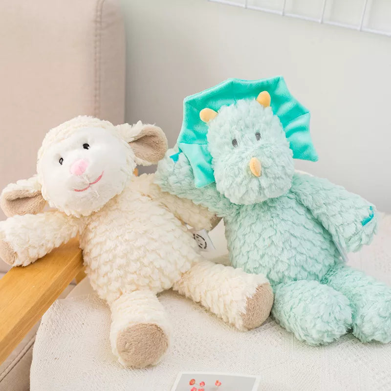 peluche mouton claire et dinosaure bleu mis en scène dans un fauteuil