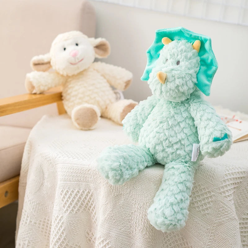 peluche mouton claire et dinosaure bleu mis en scène sur un tissu blanc