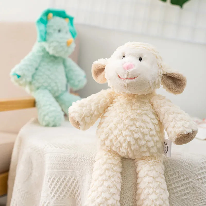peluche mouton claire et dinosaure bleu mis en scène sur un tissu blanc