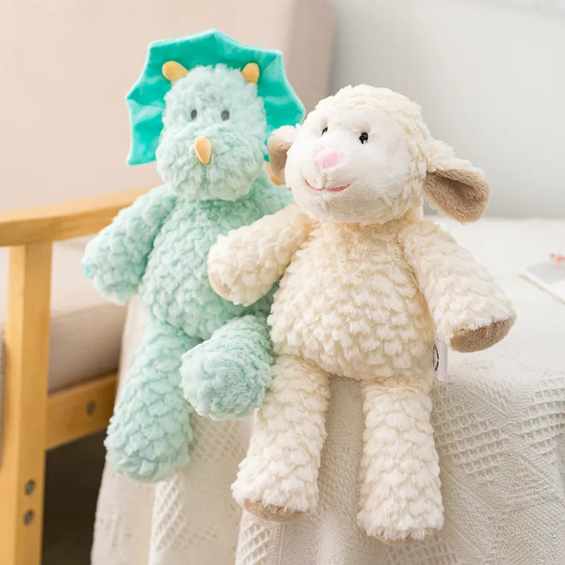 peluche mouton claire et dinosaure bleu mis en scène sur un tissu blanc