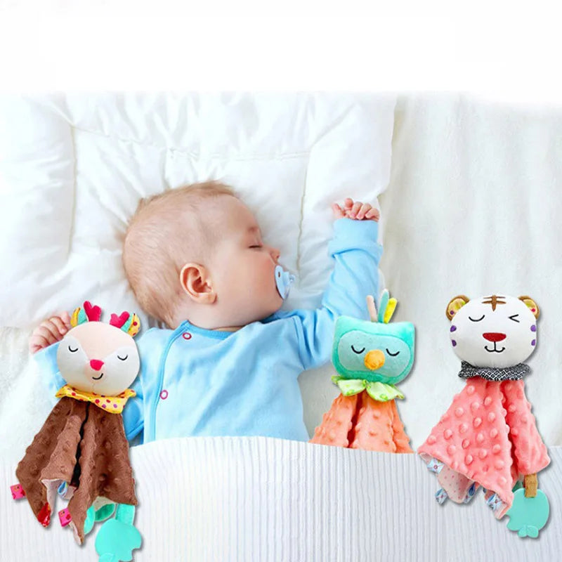 doudou hiboux orange à tête bleu, doudou tigre rose à tête blanche, et doudou biche marron à tête crème posés dans le lit aux cotés d'un bébé endormi