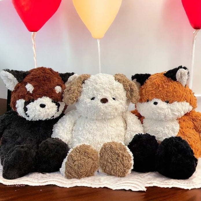 peluche raton laveur marron blanc et noir, peluche chien blanc et marron aux côtés de la peluche renard orange , blanche et noir ( de face )