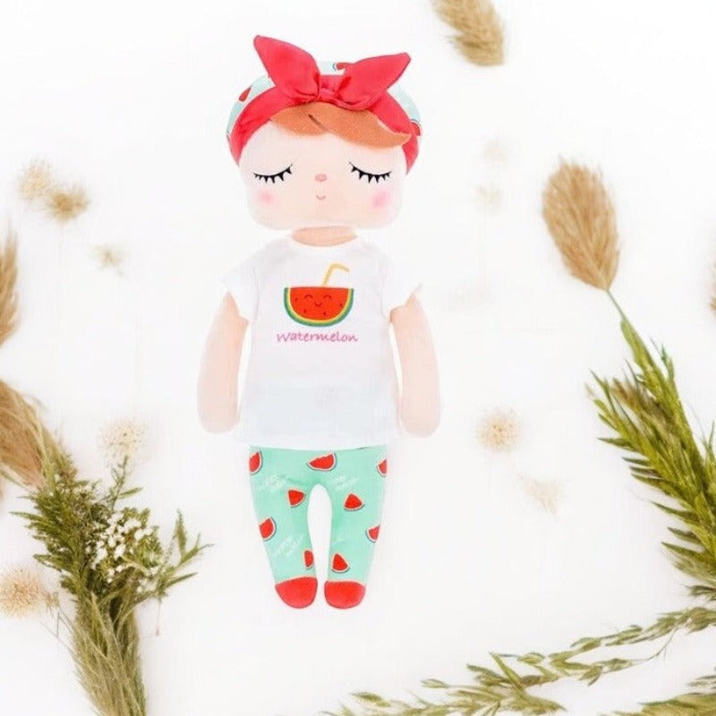 MASHA, la fée dolls de 34 cm, émerveille avec son t-shirt blanc orné d'un morceau de pastèque, son pantalon et son bonnet bleu ciel parsemés de morceaux de pastèque. Son bandeau à gros nœud et ses ballerines rouges ajoutent une touche de magie à son allure.