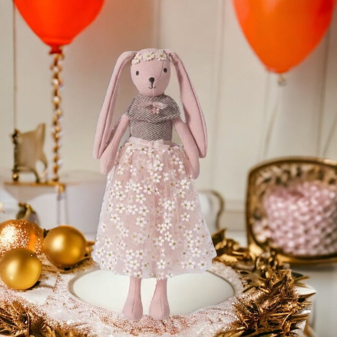 Doudou lapin robe à fleurs blanche, ceinture de satin nouée à la taille, haut de laine marron et blanche avec petite broche bijou et une couronne de fleurs sur la tête