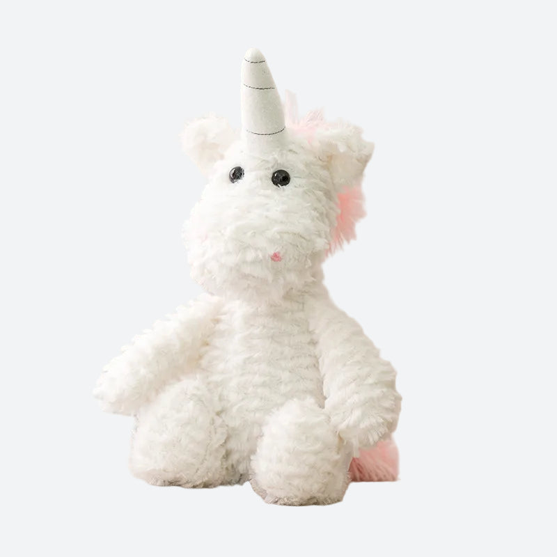 Peluche licorne blanche et rose posée sur le cananpé beige