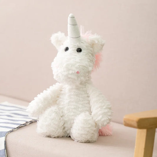 Peluche licorne blanche et rose posée sur le cananpé beige