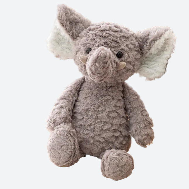 peluche éléphant gris posé sur un pouf en rotin contre un canapé bois et tissu clair 