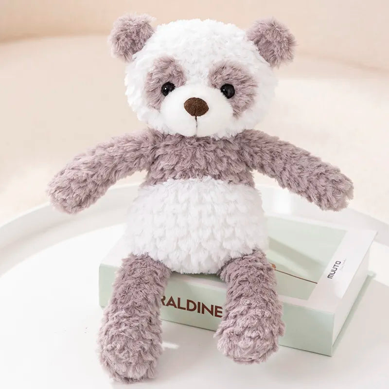 peluche panda grise et blanche posée sur un livre blanc, sur un tissu blanc sur une table ronde blanche