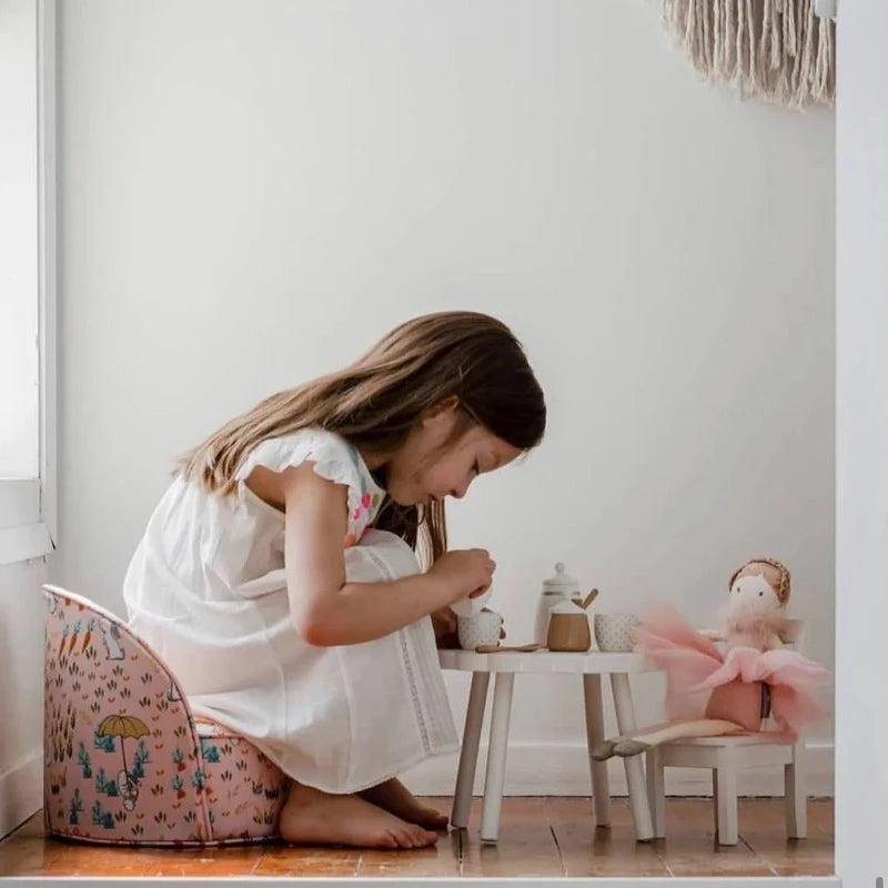 Une fillette jouant à la dinette avec son doudou fée