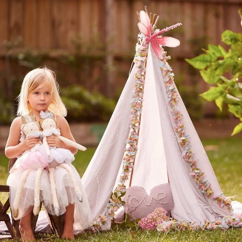 une enfant jouant avec ses deux doudous fées dans son jardin