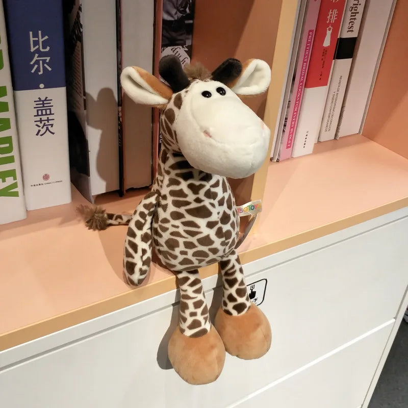 Peluche girafe - BASILE posé sur une étagère de bibliothèque photo de 3/4 gauche