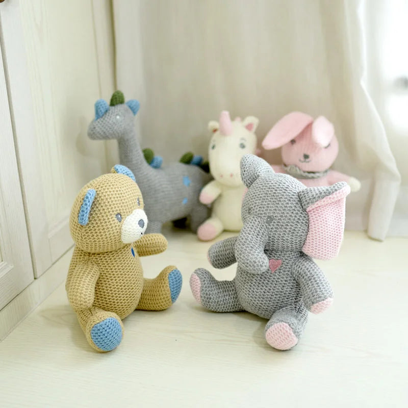 Les amis tricotés ; l’éléphant UGO, le lapin KILIAN, l’ours BILAL, la licorne JANICE, KAMIL le dinosaure et la licorne MANOE sont regroupés sur un revêtement blanc
