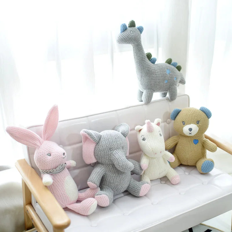 Les amis tricotés ; l’éléphant UGO, le lapin KILIAN, l’ours BILAL, la licorne JANICE, et la licorne MANOE sont regroupés sur un petit canapé clair