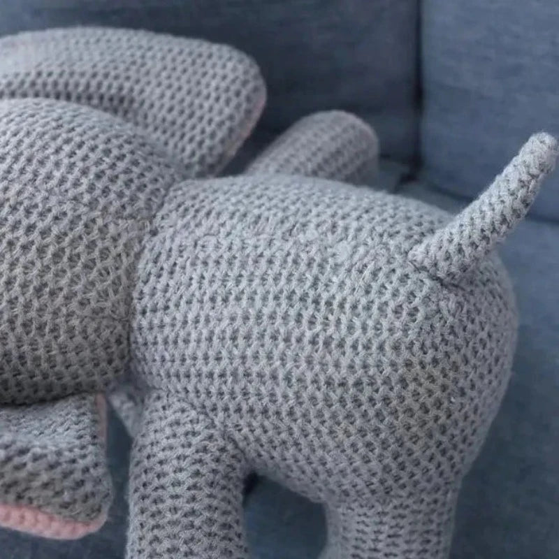  la peluche éléphant UGO. Mesurant 25 cm, cette adorable créature tricotée gris et rose, avec un petit cœur rose sur la poitrine, émerveillera votre enfant par sa tendresse et son charme féérique.  zoom sur  sa jolie queue tricoté et ses coutures dorsales