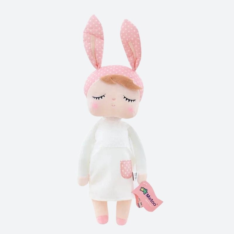 Faites la rencontre de NOVA, le doudou fée dolls de 34 cm, une créature féerique aux oreilles de lapin rose et à la robe blanche ornée d'une poche rose à pois blancs. Avec ses ballerines roses et son sourire radieux, elle est prête à partager son monde merveilleux avec votre enfant. Image