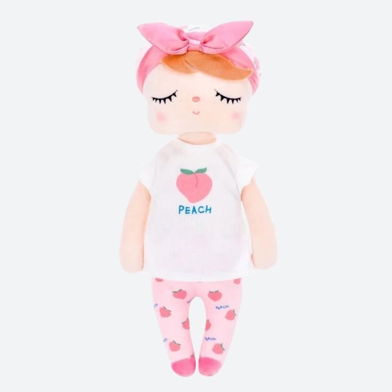 PATY, la fée dolls de 34 cm, émerveille avec son t-shirt blanc orné d'une pêche juteuse, son pantalon rose parsemé de pêches, son bonnet blanc agrémenté de motifs de pêches, son bandeau et ses ballerines roses assorties.