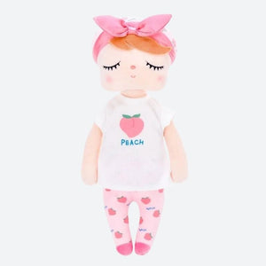 PATY, la fée dolls de 34 cm, émerveille avec son t-shirt blanc orné d'une pêche juteuse, son pantalon rose parsemé de pêches, son bonnet blanc agrémenté de motifs de pêches, son bandeau et ses ballerines roses assorties.