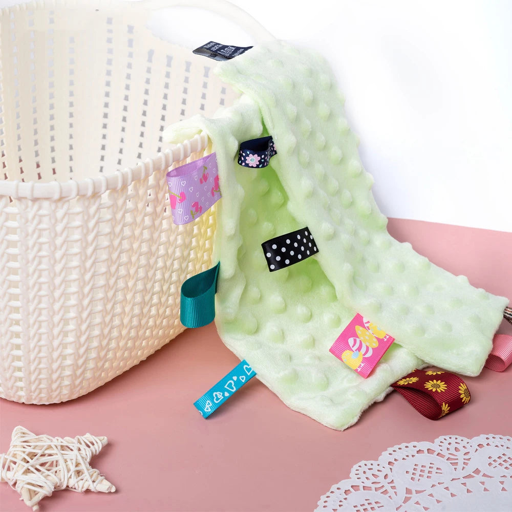 Doudou carré - COLORIA vert posé sur un panier blanc