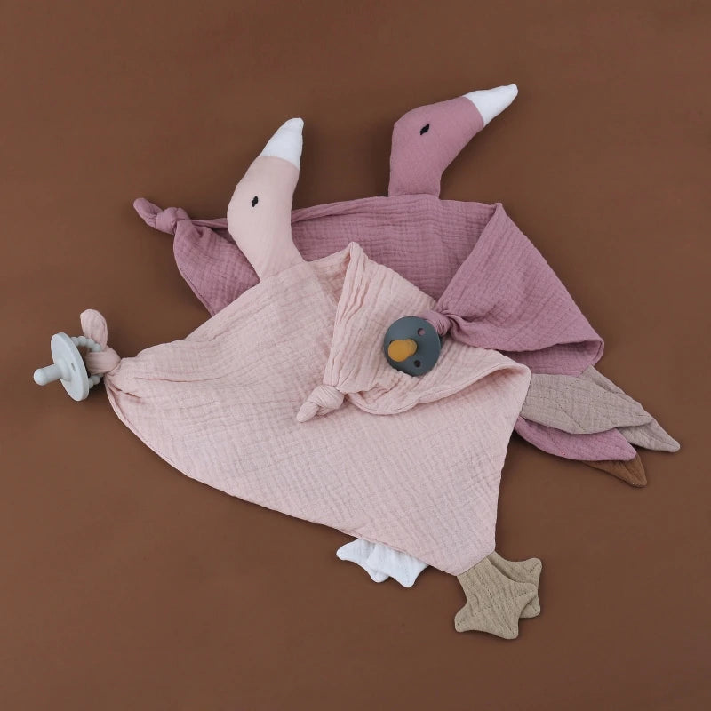 doudou gaze de coton oie, se présente en 9 couleurs éclatantes. Son design plat en triangle et ses détails astucieux, tels que deux grandes étiquettes à machouiller et deux noeuds attache tétine aux bouts des ailes avec le bec blanc et des pattes palmées, en font un doudou magnifique et fonctionnel, conçu dans une délicate gaze de coton.