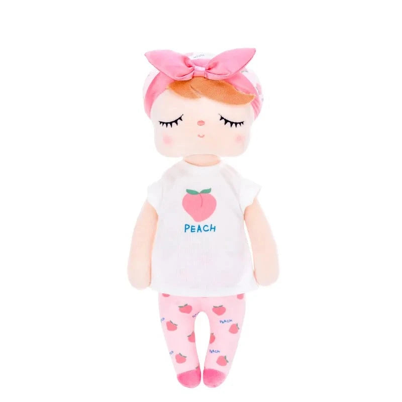 PATY, la fée dolls de 34 cm, émerveille avec son t-shirt blanc orné d'une pêche juteuse, son pantalon rose parsemé de pêches, son bonnet blanc agrémenté de motifs de pêches, son bandeau et ses ballerines roses assorties.