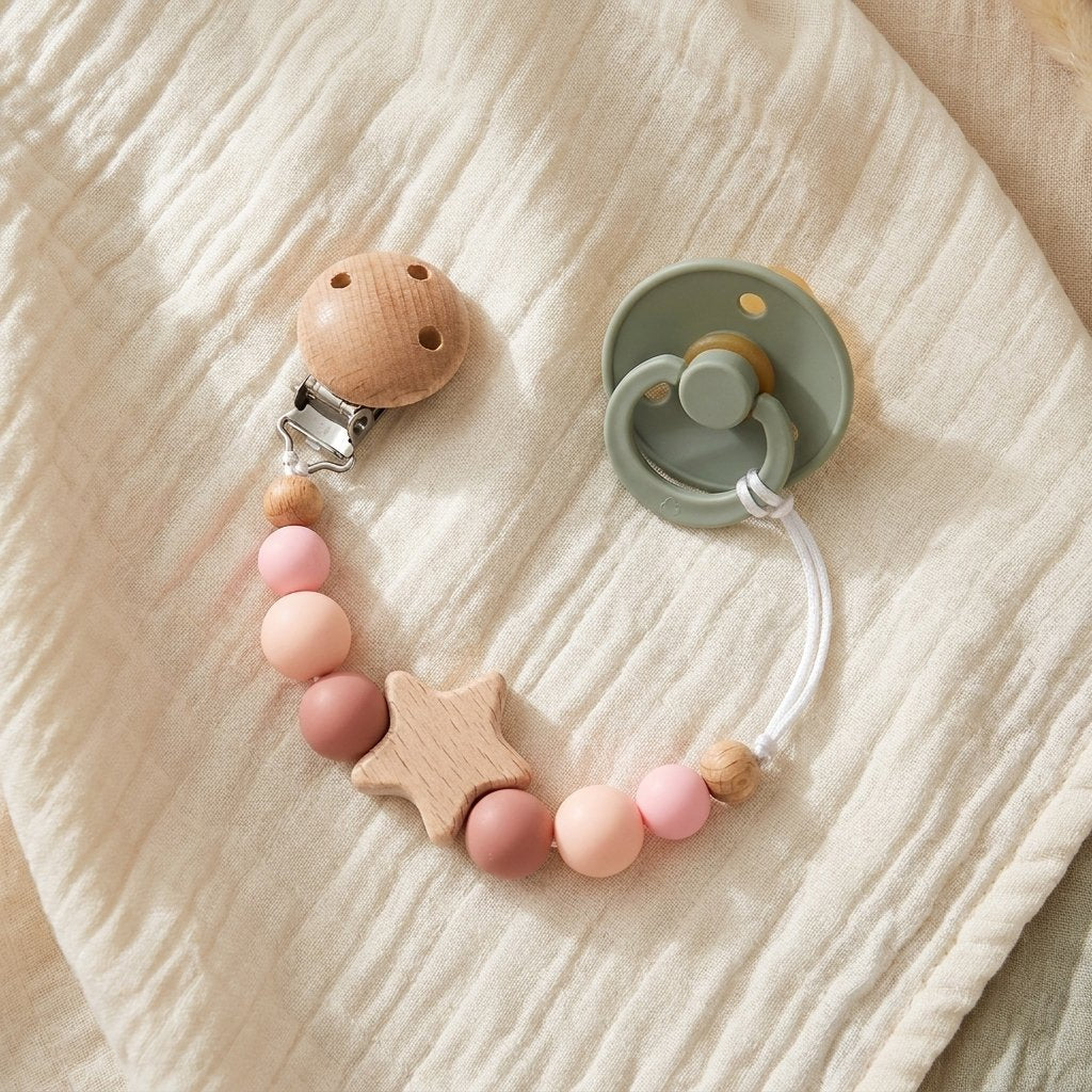 Attache-tétine perles rose reliée à une tétine sur un lange Image