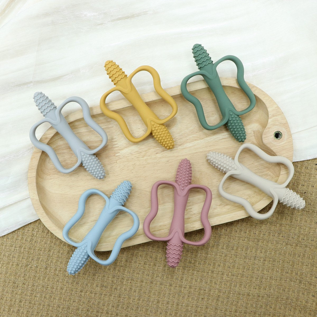 Jouets de dentition à poignées de plusieurs couleurs sur un plateau en bois Image