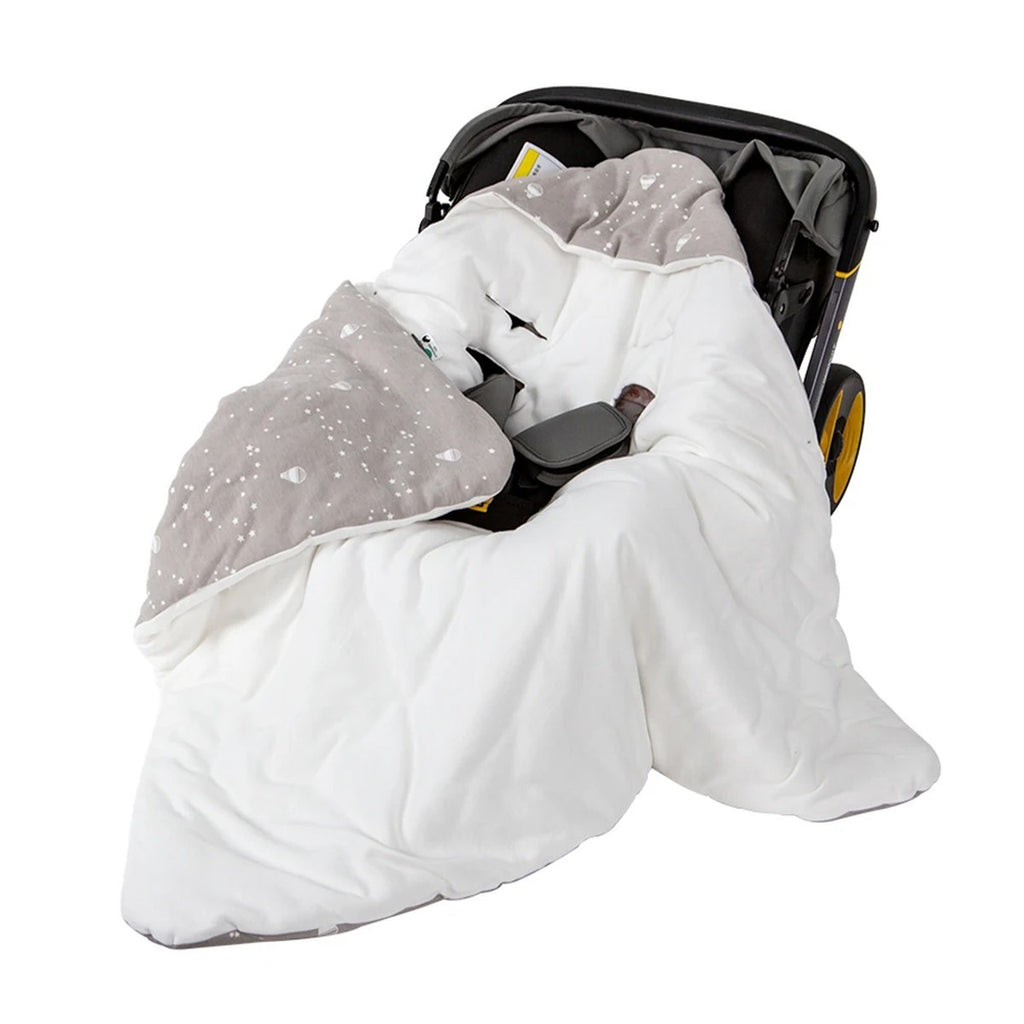 Nid d'ange cosy blanc et gris étoilé installé dans un siège auto coque