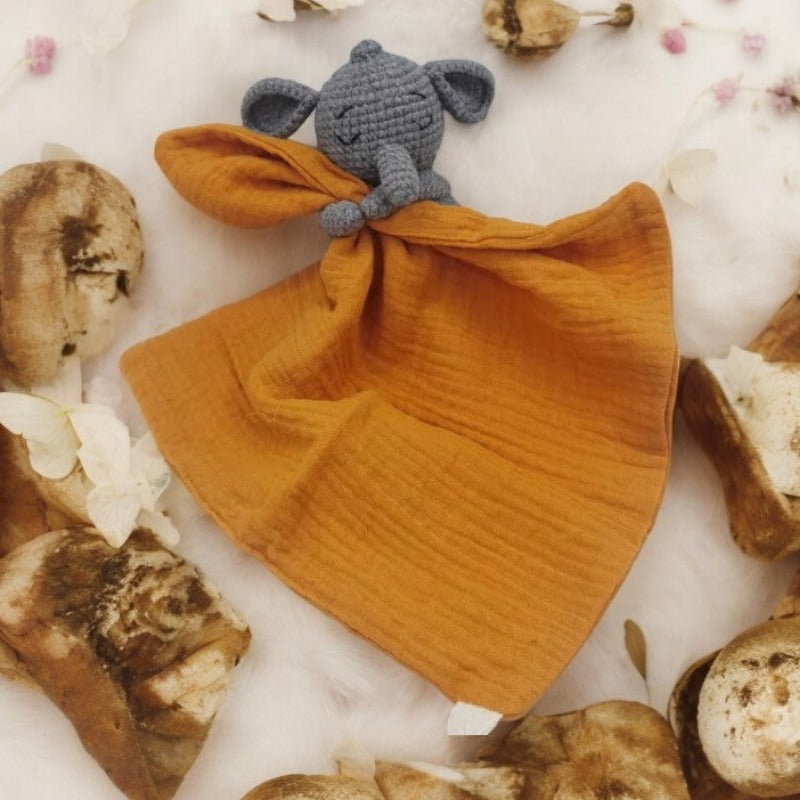 FABIO est un adorable doudou plat représentant un éléphant au crochet. Il tient un carré de tissu gaze de coton ou mouchoir entre ses pattes, offrant confort et réconfort à votre enfant. Disponible en plusieurs coloris de mouchoir : orange, vert et gris. ORANGE Image