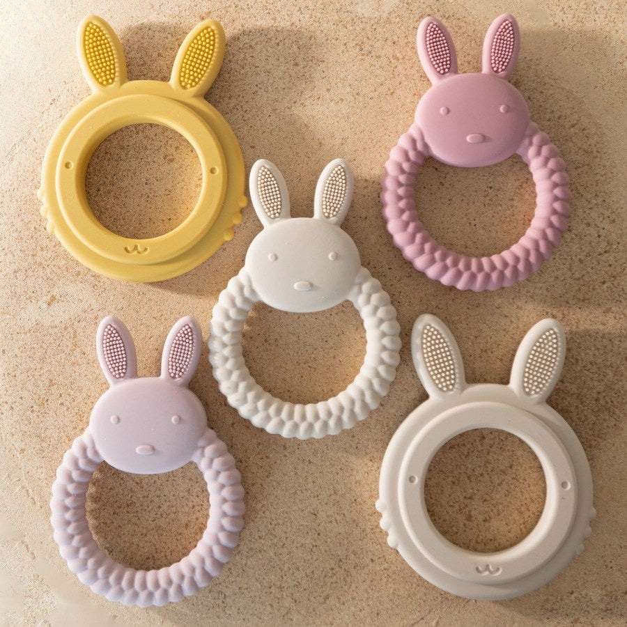 Anneaux de dentition lapin de plusieurs couleurs sur du sable