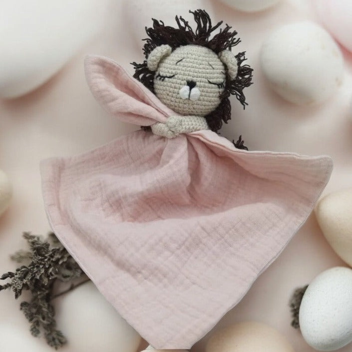 EROS est un adorable doudou plat représentant un lion au crochet. Il tient un mouchoir ou carré de gaze de coton entre ses pattes, offrant à votre enfant douceur et réconfort. Disponible en plusieurs coloris : Écru, Rose pâle, Bleu, Vieux rose et Vert. ROSE PALE