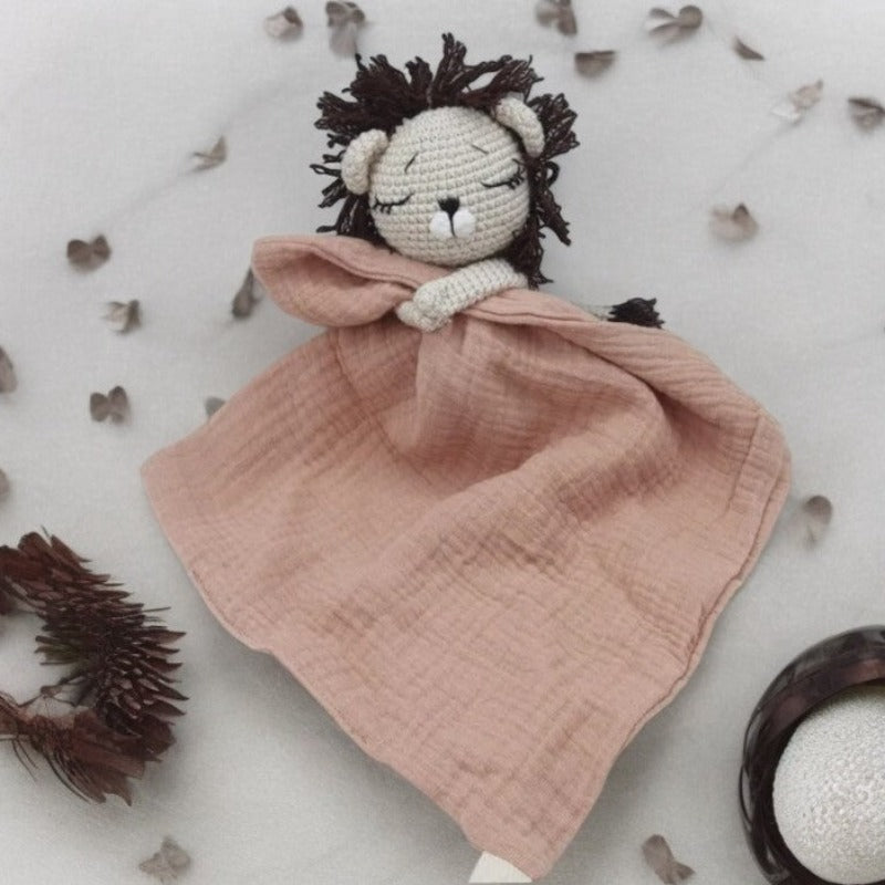 EROS est un adorable doudou plat représentant un lion au crochet. Il tient un mouchoir ou carré de gaze de coton entre ses pattes, offrant à votre enfant douceur et réconfort. Disponible en plusieurs coloris : Écru, Rose pâle, Bleu, Vieux rose et Vert. VIEUX ROSE