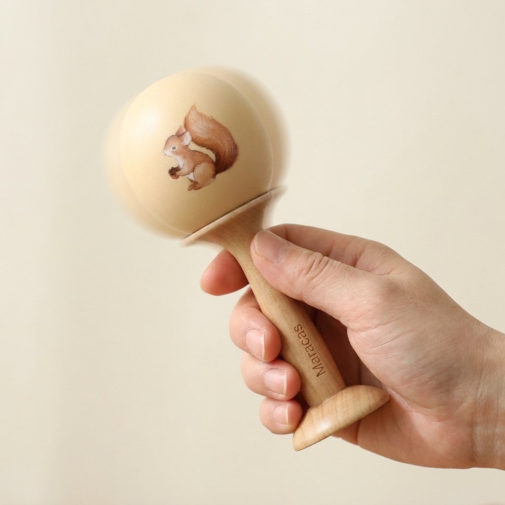 Main secouant une maraca en bois