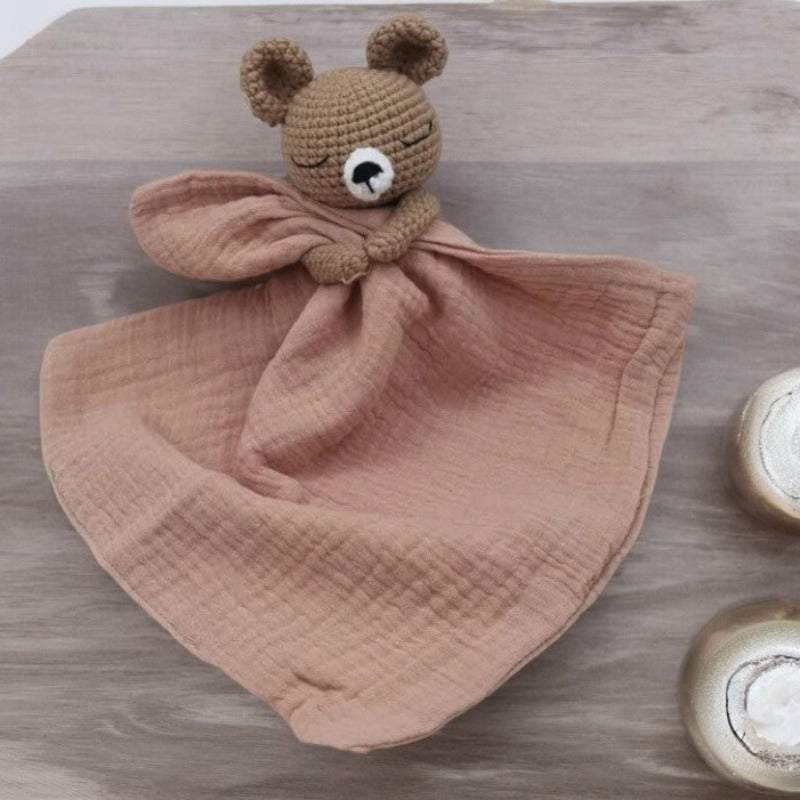 BARAT est un doudou plat représentant un adorable ours marron au crochet. Il tient un carré de tissu gaze de coton ou mouchoir entre ses pattes, pouvant également être utilisé comme attache tétine. Disponible avec 5 coloris de mouchoir : crème, vieux rose, rose pâle, écru et bleu. VIEUX ROSE