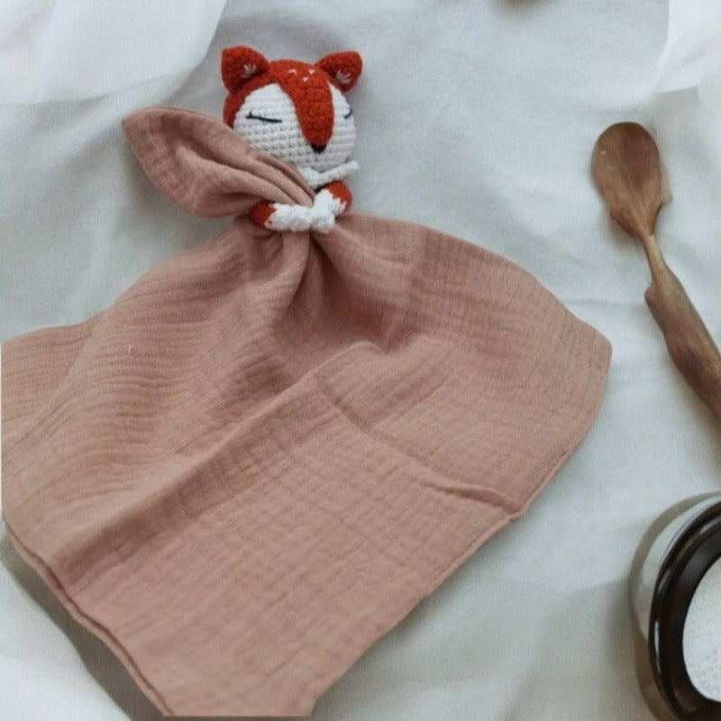 VIGOT est un doudou plat représentant un renard au crochet, de couleur orange et blanc, tenant un carré de tissu gaze de coton ou mouchoir entre ses pattes. Disponible avec 4 coloris de mouchoir : vieux rose, écru, bleu et vert. VIEUX ROSE