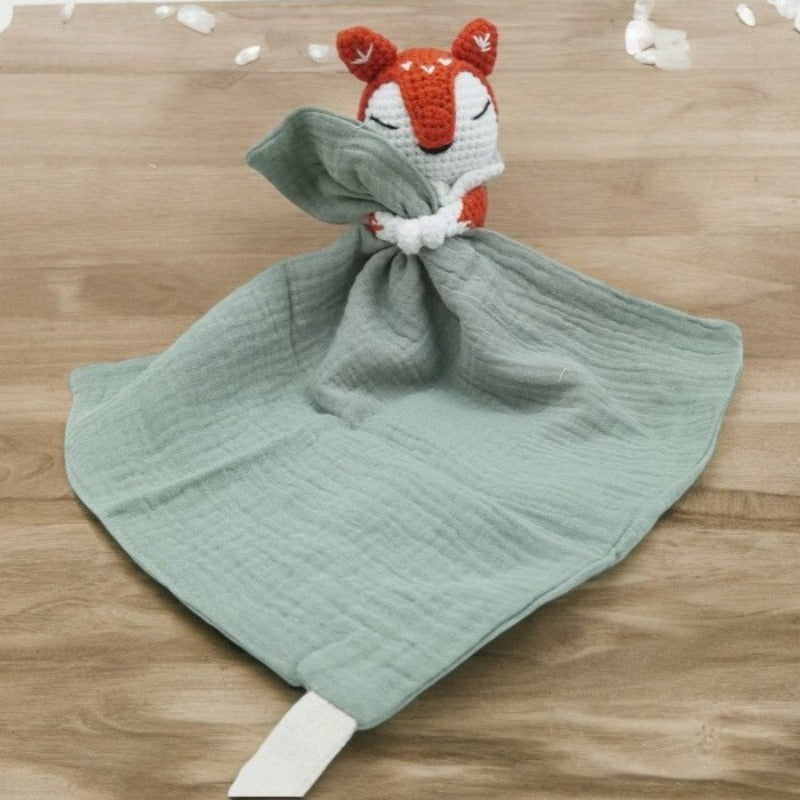 VIGOT est un doudou plat représentant un renard au crochet, de couleur orange et blanc, tenant un carré de tissu gaze de coton ou mouchoir entre ses pattes. Disponible avec 4 coloris de mouchoir : vieux rose, écru, bleu et vert. VERT