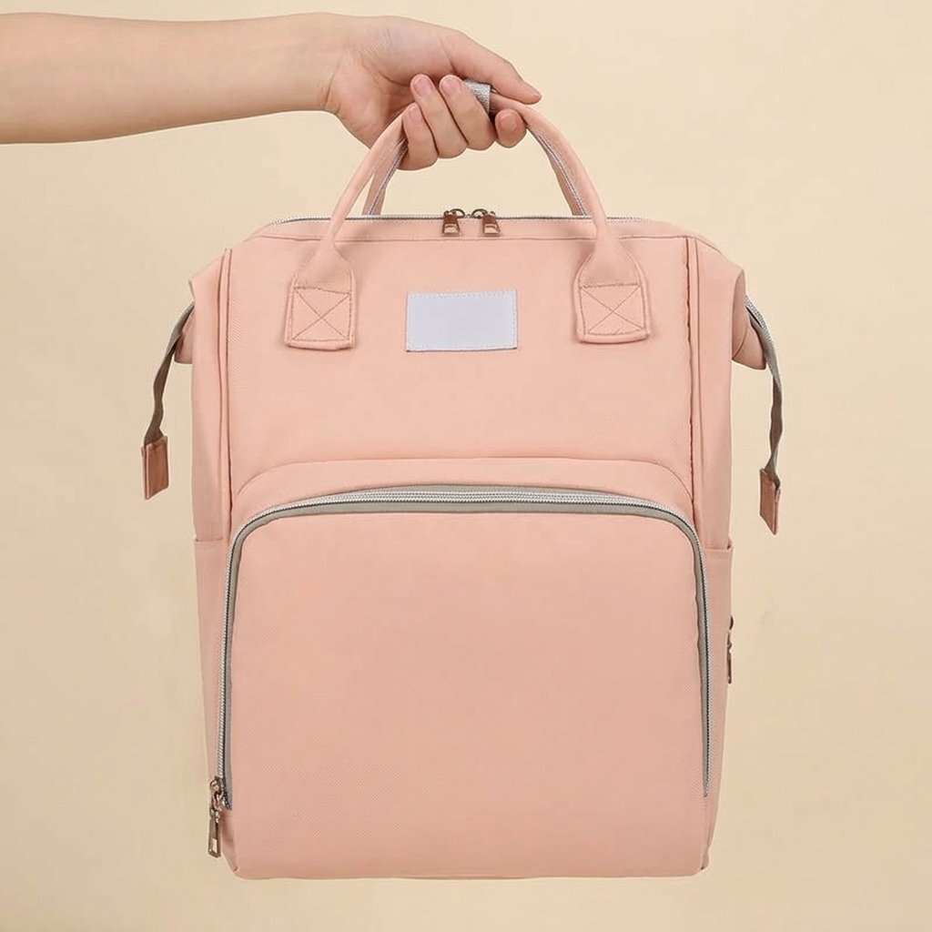 Main portant le sac à dos à langer rose par ses poignées